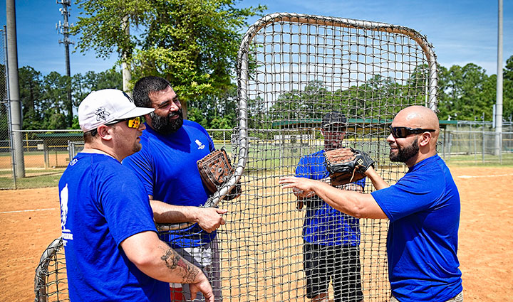 Men in blue shirts setting up baseball equipment